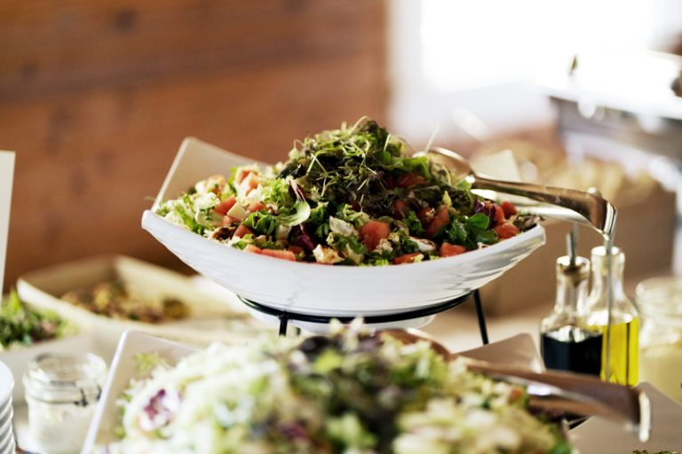 noutopöytä, ruokaisia salaatteja ja salaatinkastikkeet, taustalla hirsiseinä