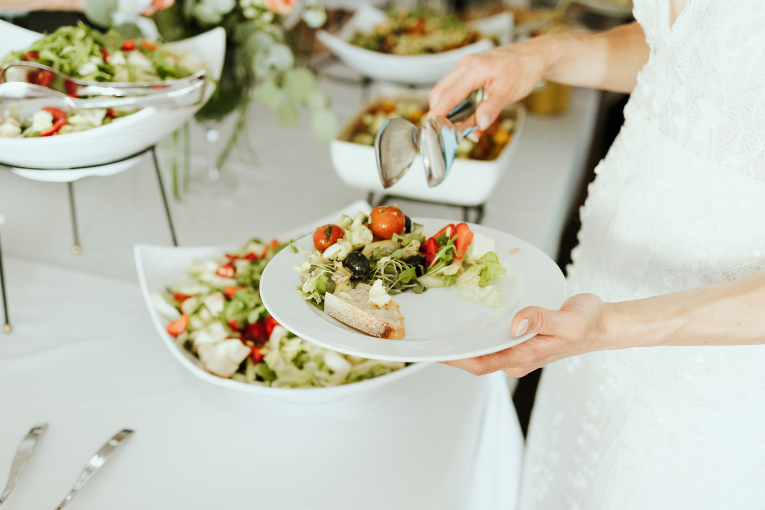 Morsian nostaa salaattia lautaselleen buffetpöydässä.
